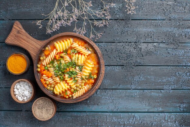Vista superior de sopa de pasta en espiral deliciosa comida con diferentes condimentos en el escritorio oscuro colores de la sopa plato de pasta italiana cocina
