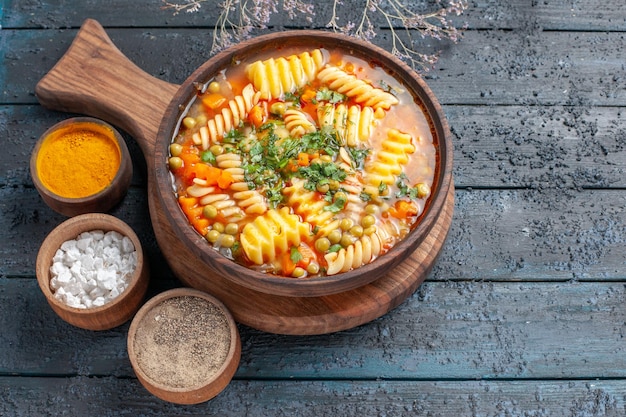 Vista superior sopa de pasta en espiral deliciosa comida con diferentes condimentos en el piso oscuro color de la sopa plato de pasta italiana cocina