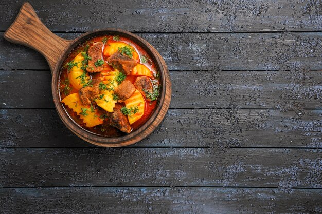 Vista superior de la sopa de salsa de carne con patatas y verduras en el escritorio oscuro