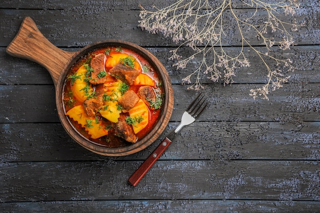 Vista superior de la sopa de salsa de carne con verduras y patatas en el escritorio oscuro