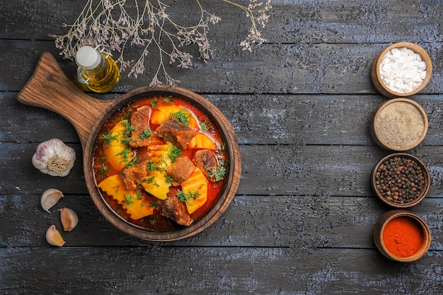 Vista superior de la sopa de salsa de carne con verduras y patatas en el escritorio oscuro