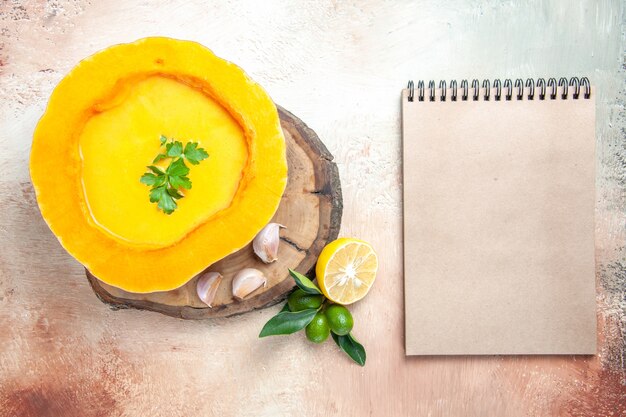 Vista superior sopa sopa de calabaza con hierbas ajo crema de limón cuaderno