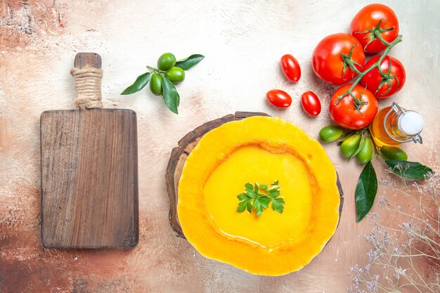 Vista superior de la sopa sopa de calabaza en el tablero cuchara tomates cítricos aceite la tabla de cortar