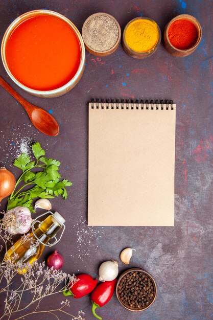 Vista superior de la sopa de tomate cocinada con tomates frescos con diferentes condimentos en el cuadro negro