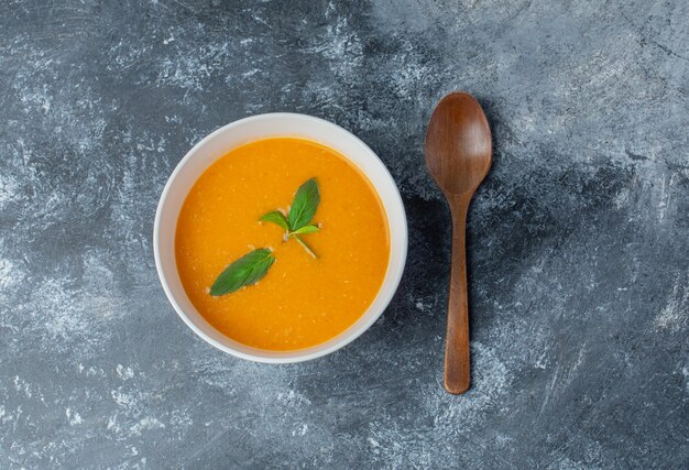 Vista superior de sopa de tomate fresco y cuchara de madera.