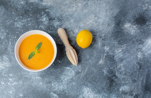 Vista superior de la sopa de tomate y limón fresco con exprimidor de limón.