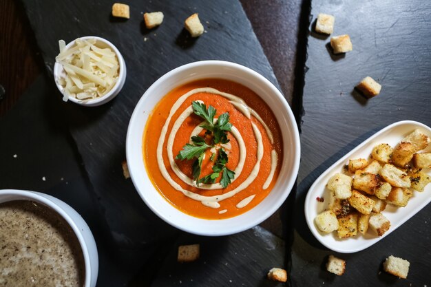 Vista superior sopa de tomate con queso y galletas en un soporte