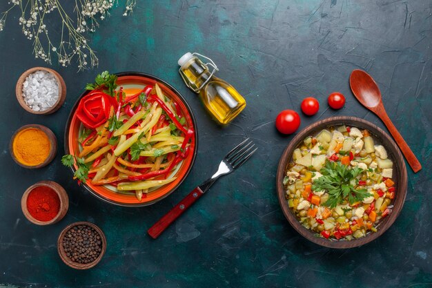 Vista superior de sopa de verduras con diferentes condimentos y ensalada picante sobre fondo azul oscuro