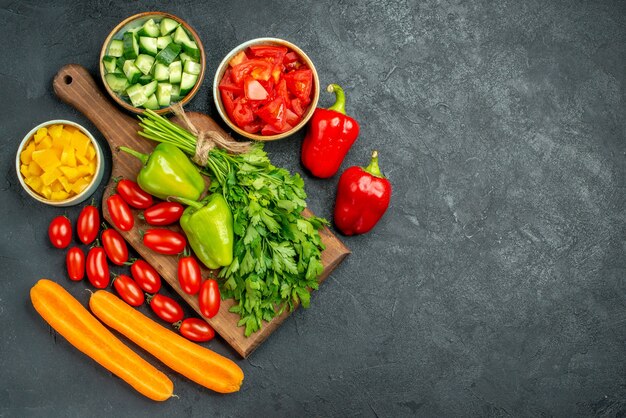 Vista superior del soporte para platos con verduras encima y cerca de él y lugar libre para el texto sobre fondo gris oscuro