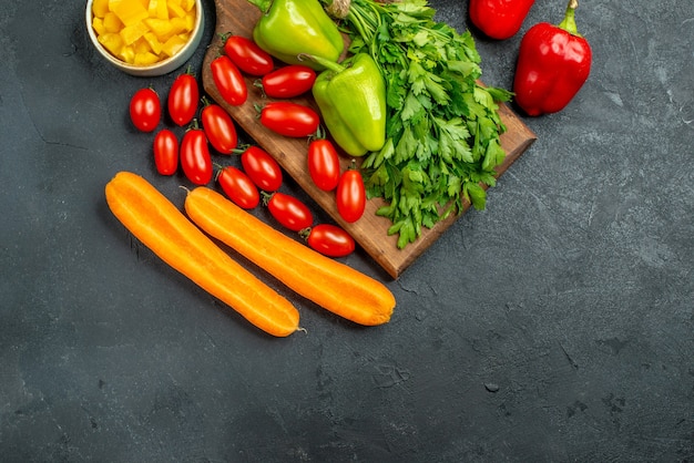 Vista superior del soporte para platos con verduras encima y cerca de él con lugar libre para el texto sobre fondo gris oscuro