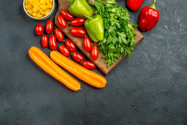 Vista superior del soporte para platos con verduras encima y cerca de él con lugar libre para el texto sobre fondo gris oscuro