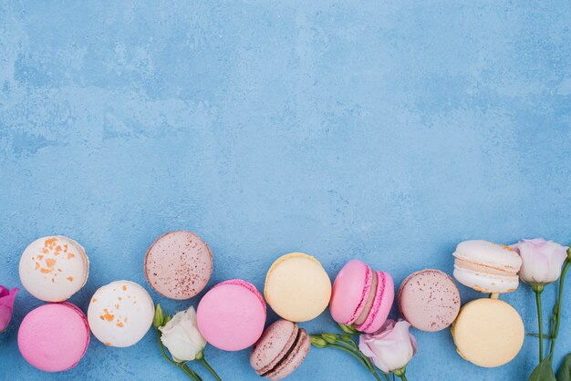 Vista superior de surtido de macarons con rosas y espacio de copia