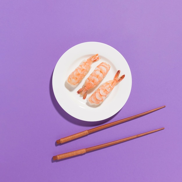 Vista superior sushi fresco con palillos sobre la mesa