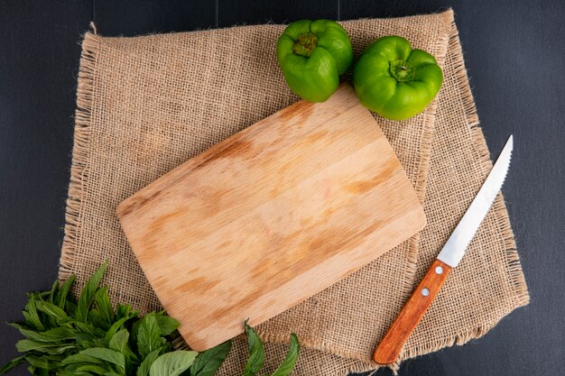 Vista superior de la tabla de cortar con cuchillo de pimiento y menta en una servilleta beige