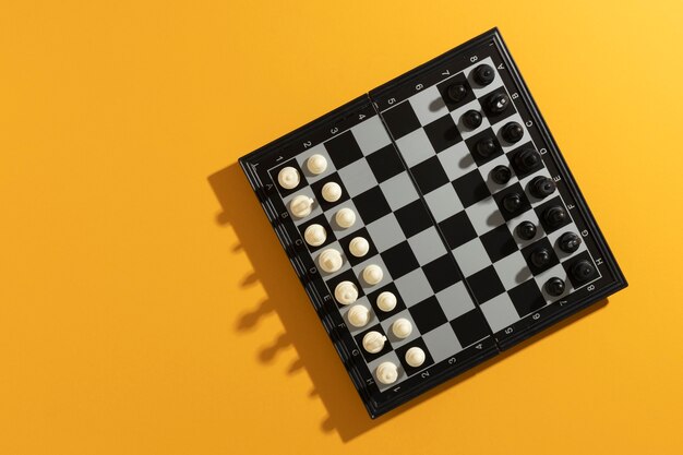 Vista superior del tablero de ajedrez con piezas sobre fondo amarillo