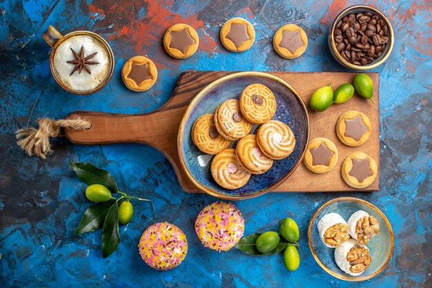 Vista superior desde el tablero de madera de dulces lejanos con galletas junto a los diferentes dulces granos de café