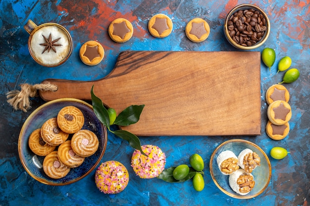 Vista superior desde el tablero de madera de dulces lejanos junto a los diferentes dulces galletas granos de café