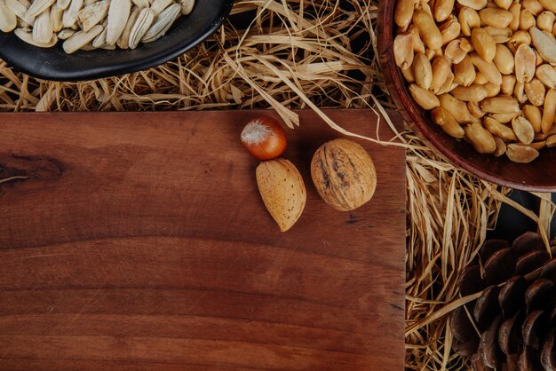 Vista superior de un tablero de madera con nueces y cerveza aperitivos en paja