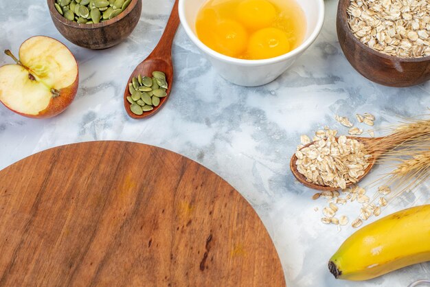 Vista superior de tablero redondo de madera e ingredientes para la comida saludable sobre fondo blanco manchado