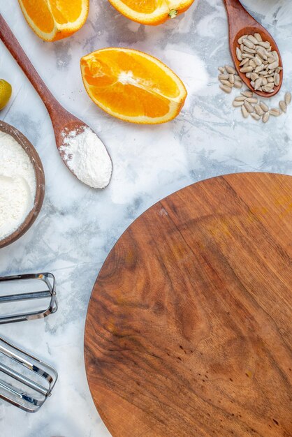 Vista superior del tablero redondo de madera y los ingredientes para la comida saludable en la mesa azul blanca