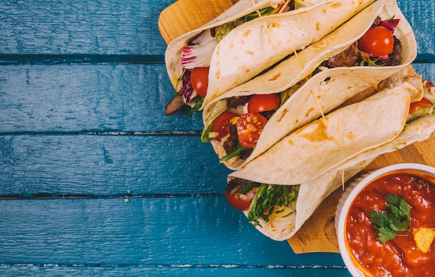 Foto gratuita vista superior de tacos mexicanos; salsa de salsa con carne y verduras en tabla para cortar