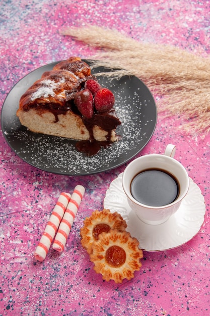 Vista superior de tarta de chocolate con fresa con taza de té y escritorio rosa claro