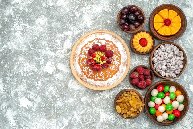 Vista superior de la tarta de frambuesa con dulces y pasas en la superficie blanca tarta de pastel de galletas de frutas