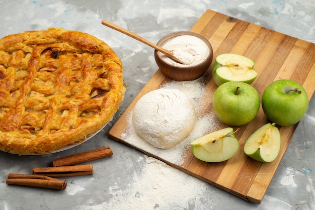 Una vista superior de la tarta de manzana redonda formada deliciosa con harina de manzanas frescas sobre el fondo blanco pastel de galletas