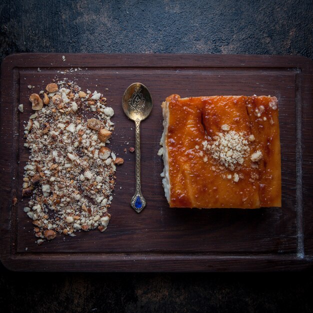 Vista superior tarta con migas de nuez y cuchara antigua en tablero de alimentos