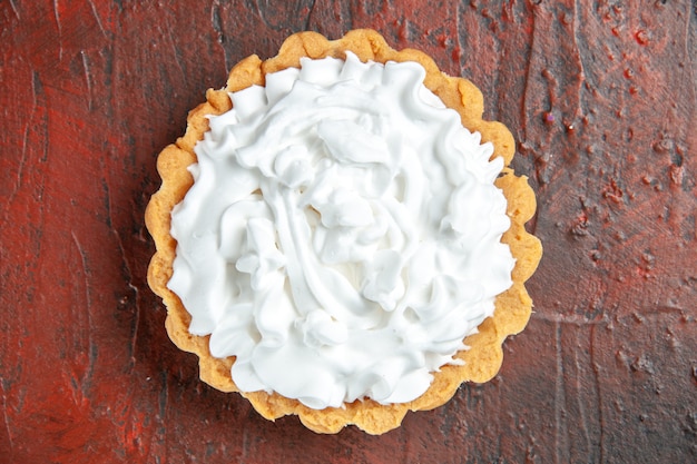 Foto gratuita vista superior de la tarta pequeña con crema pastelera en la superficie de color rojo oscuro