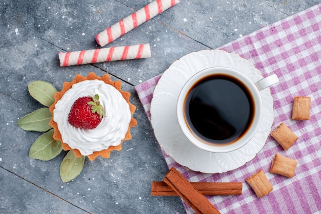 Vista superior de la taza de café caliente y fuerte junto con pastel y canela en gris, caramelo de café, bebida dulce, galleta de cacao