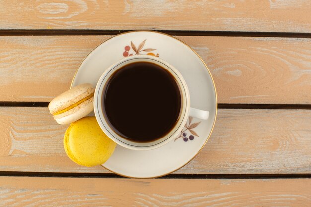 Vista superior de una taza de café caliente y fuerte con macarons franceses en el escritorio rústico de color crema beber café fuerte foto