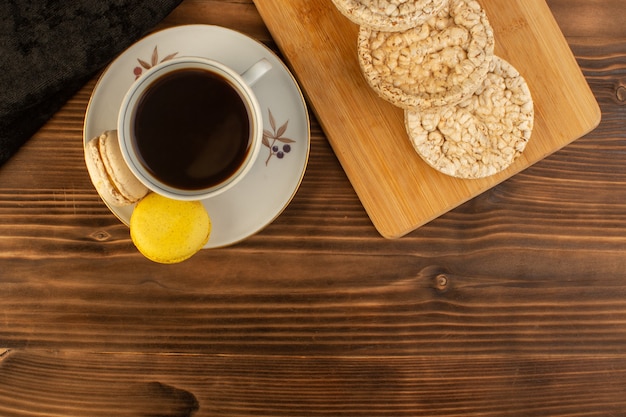 Vista superior de una taza de café caliente y fuerte con macarons franceses y galletas en la mesa rústica de madera marrón café bebida caliente