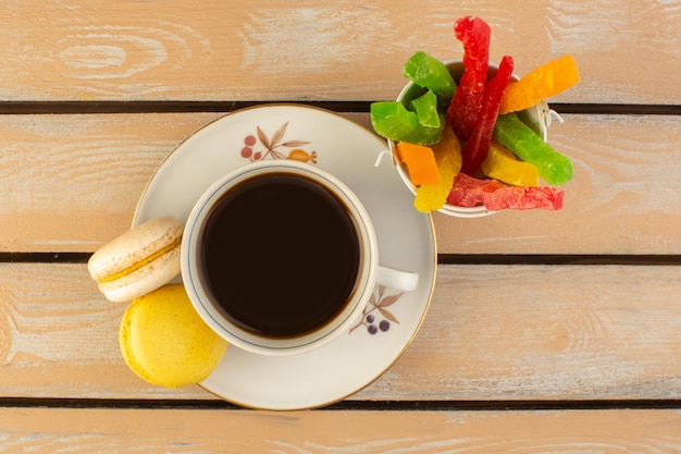 Vista superior de una taza de café caliente y fuerte con macarons franceses y mermelada en el escritorio rústico de color crema beber café foto fuerte