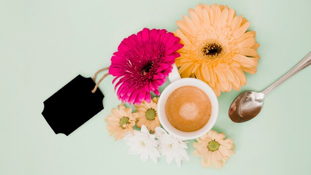 Vista superior de la taza de café con decoración de flores y etiqueta negra en blanco sobre fondo de color