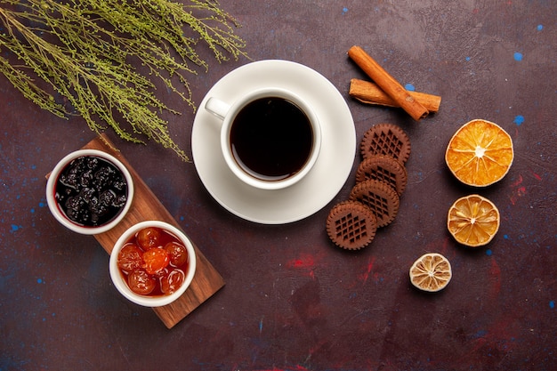 Vista superior de la taza de café con diferentes mermeladas y galletas de chocolate en el escritorio oscuro mermelada de frutas dulce mermelada