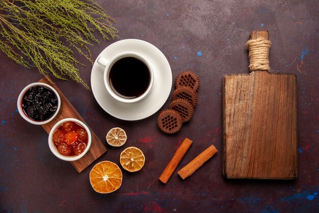 Vista superior de la taza de café con diferentes mermeladas y galletas de chocolate en el fondo oscuro mermelada de frutas dulces mermelada