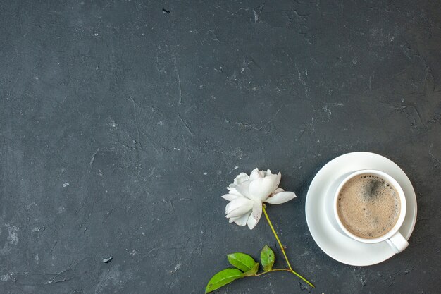 Vista superior de la taza de café con flor blanca en la mesa oscura