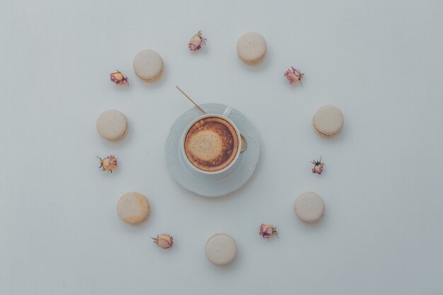 Vista superior de una taza de café con galletas y artículos decorativos en blanco