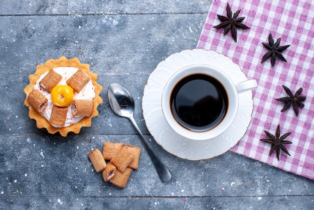 Vista superior de la taza de café con galletas formadas almohada y pastel cremoso en un escritorio brillante, masa dulce de galletas de galletas de café