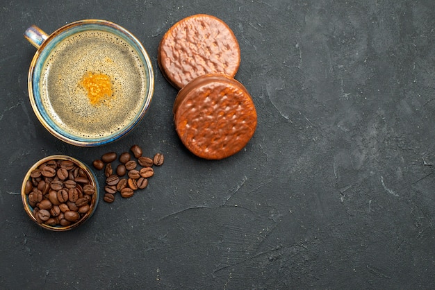 Vista superior de una taza de café con galletas de semillas de café sobre fondo oscuro aislado