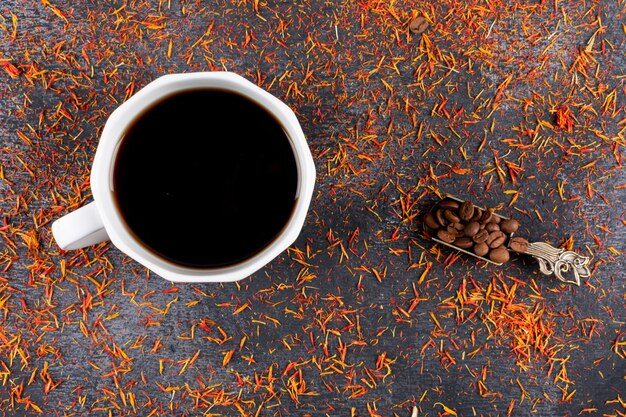 Vista superior de la taza de café con granos de café en la mesa oscura con especias