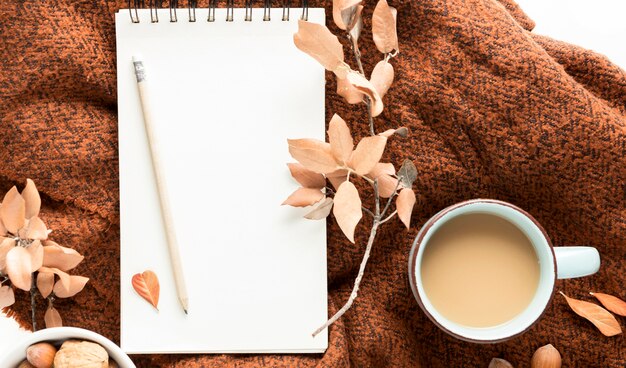 Vista superior de la taza de café con hojas de otoño y cuaderno