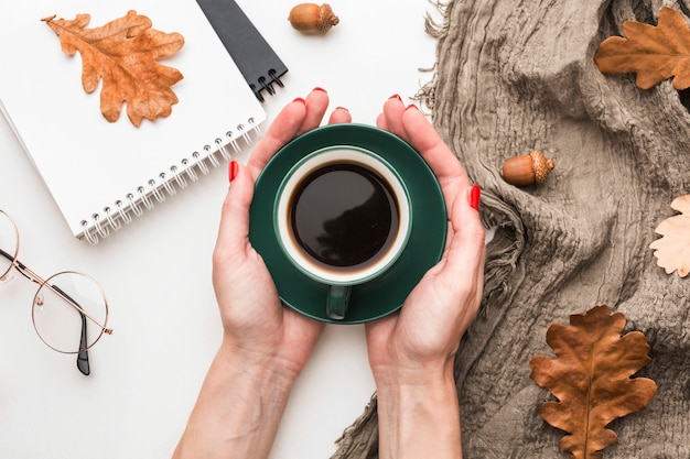 Vista superior de la taza de café con hojas de otoño y cuadernos