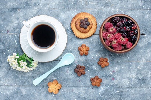 Vista superior de la taza de café junto con pequeñas galletas y bayas en madera gris, galleta de pastelería dulce hornear