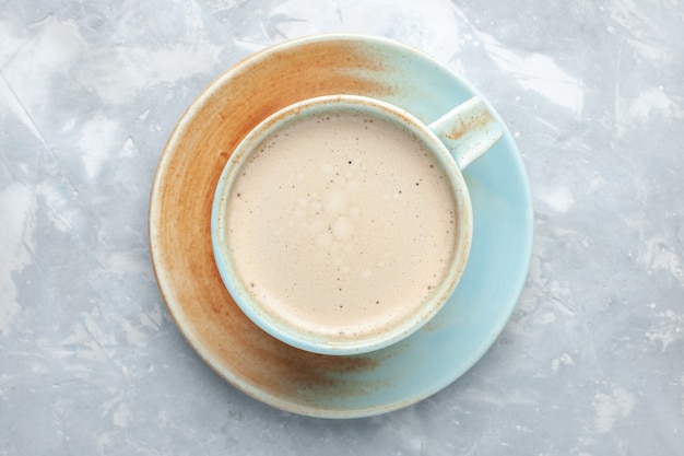 Vista superior de la taza de café con leche dentro de la taza en el escritorio blanco beber café leche color del escritorio