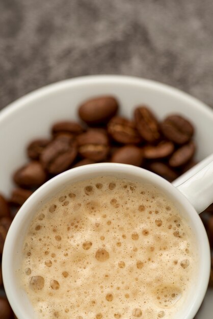 Vista superior taza de café con leche con granos tostados