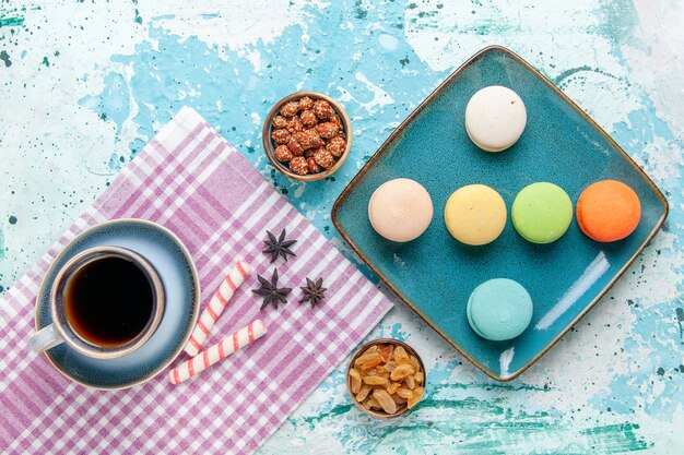 Vista superior de la taza de café con macarons franceses pasas y confituras en la superficie azul claro pastel hornear pastel de azúcar dulce galleta