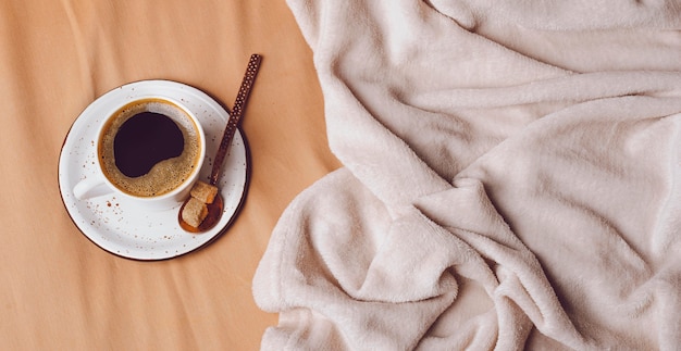 Vista superior de la taza de café de la mañana en la cama con espacio de copia