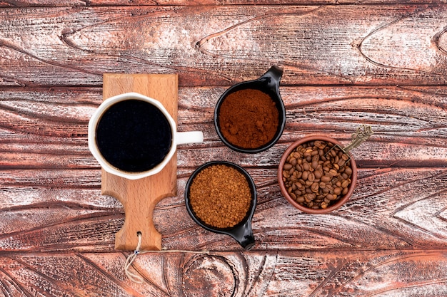 Vista superior de la taza de café en pequeños tableros de madera granos de café sobre superficie de madera